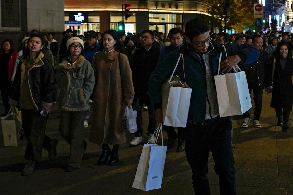 A man adjusts his bag of purchased goods as visitors tour a Nanjing pedestrian shopping street in Shanghai, China, on November 25, 2023 (AP)