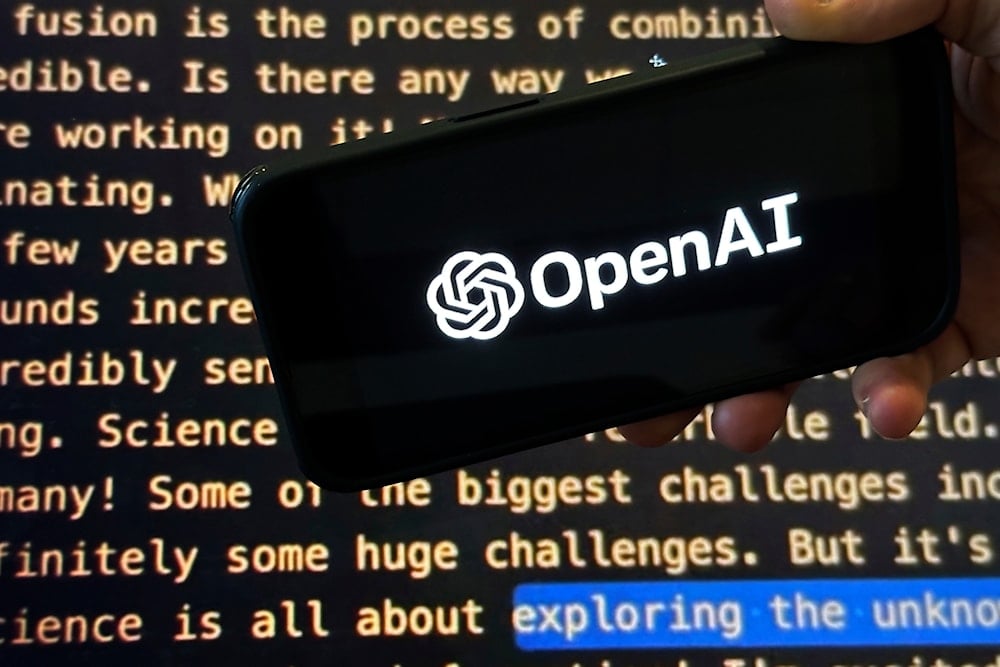 The OpenAI logo appears on a mobile phone in front of a screen showing part of the company website in this photo taken on Nov. 21, 2023 (AP)