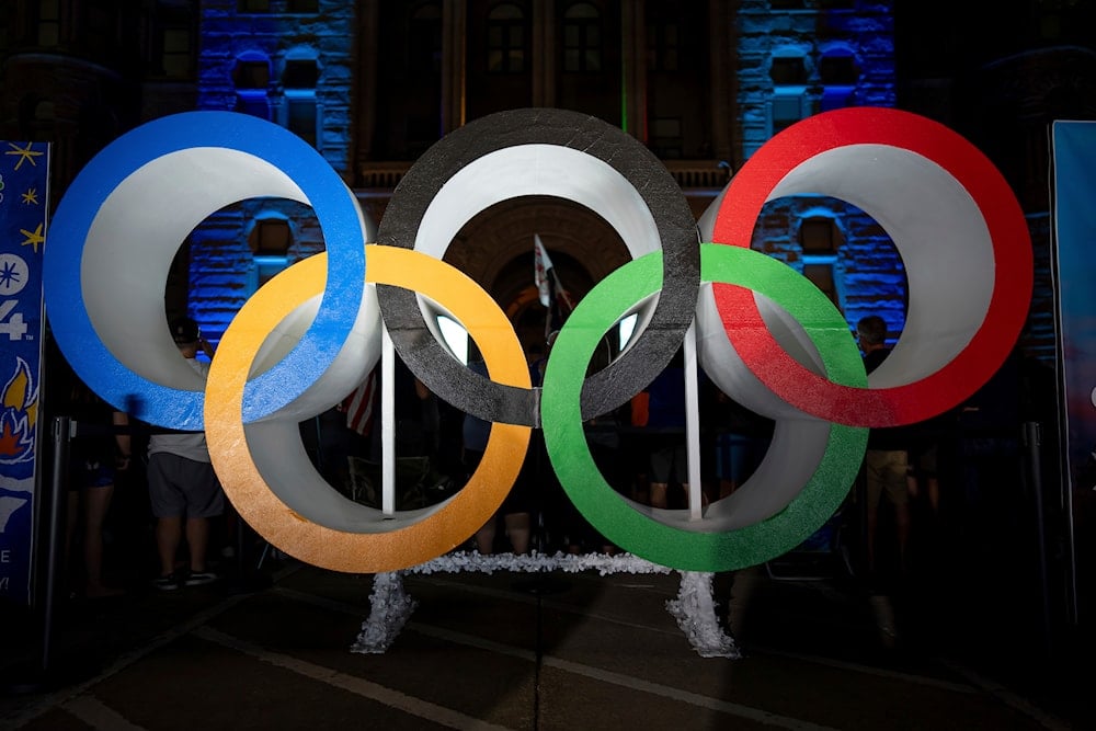 Olympic rings are pictured Wednesday, July 24, 2024, in Salt Lake City, while people gather to watch a live stream from Paris as the International Olympic Committee awards Salt Lake City the 2034 Winter Olympics (AP)