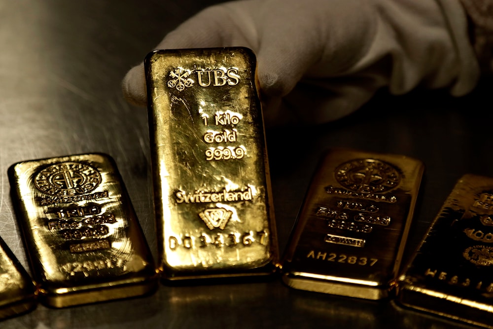 Gold inches down as dollar firms, focus on US inflation data.