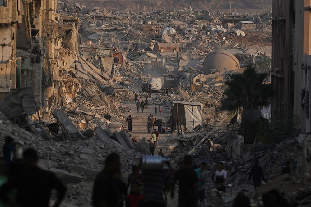 Palestinians walk through the destruction caused by the Israeli air and ground offensive in Gaza City, Thursday, October 23, 2025. (AP Photo/Abdel Kareem Hana)
