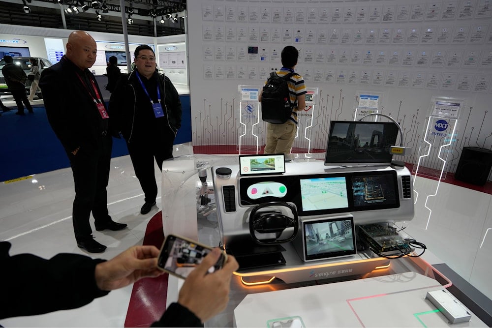 Visitors to the 2025 World Intelligent Connected Vehicles Conference stand near a depiction of a high tech car in Beijing, China, Thursday, Oct. 16, 2025. (AP)