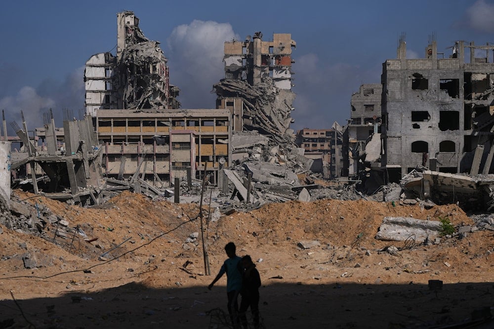 Palestinians walk through the destruction caused by the Israeli air and ground offensive in the Al-Shati camp, in Gaza City, on October 24, 2025. (AP Photo/Abdel Kareem Hana)
