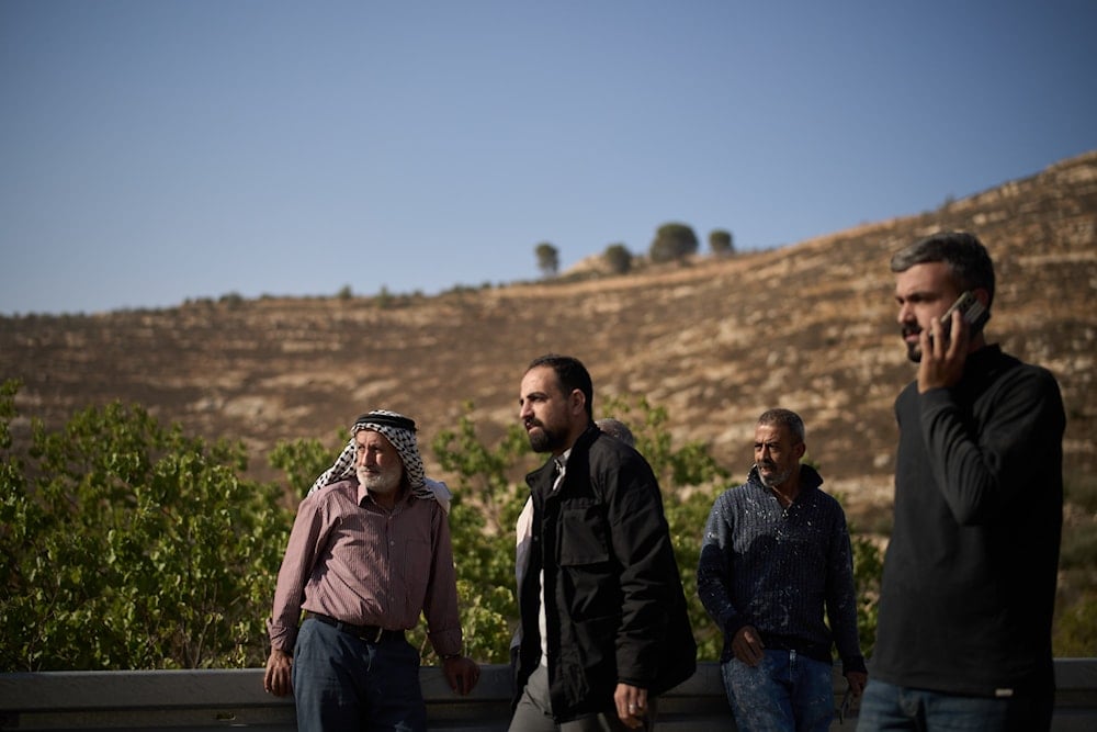 Palestinians stand on the road side after Israeli soldiers blocked access to an area for harvesting olives in the West Bank village of Sa'ir, near Hebron, on October 23, 2025. (AP Photo/Leo Correa)