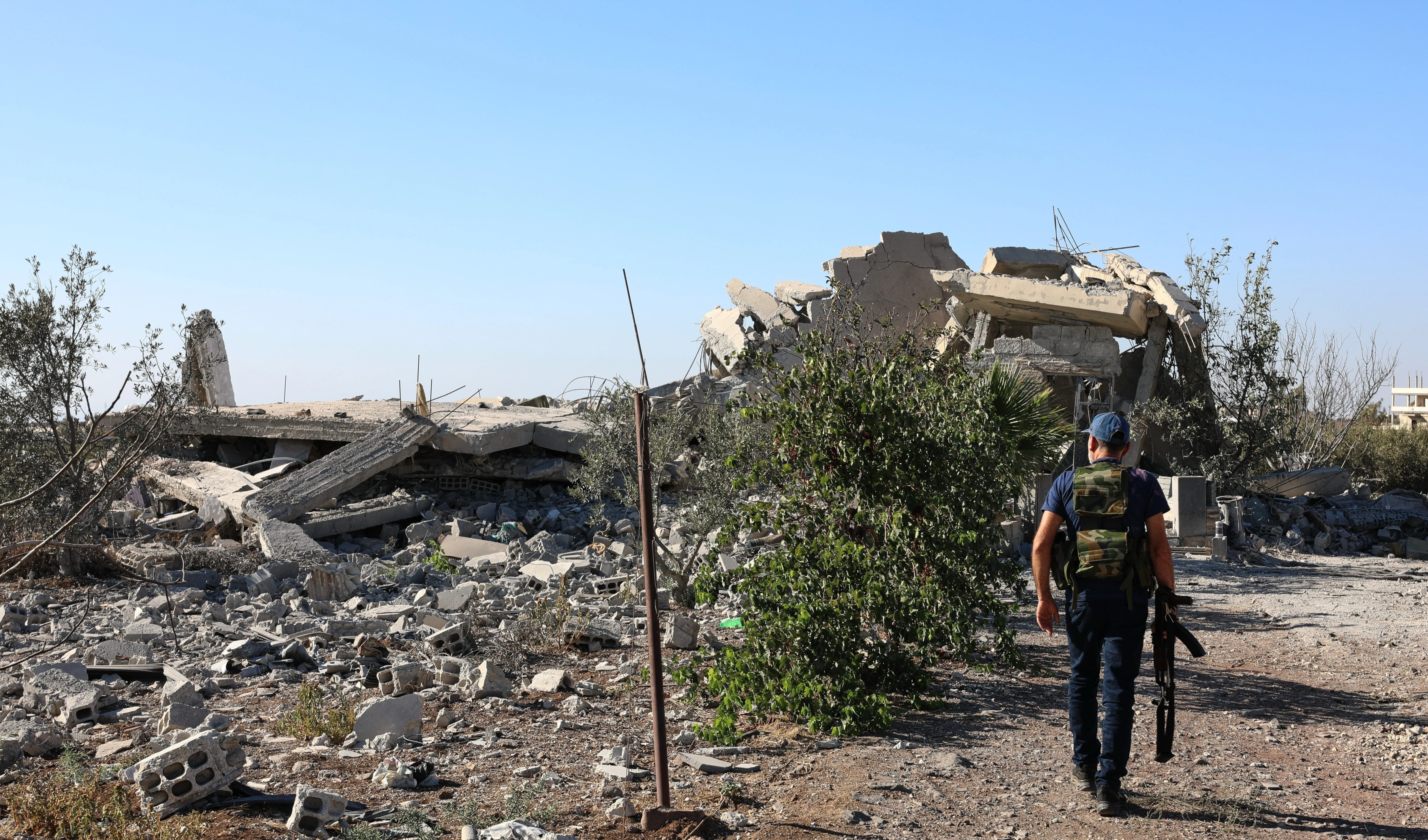 A gunman walks by the remains of a house destroyed during the recent sectarian clashes in the Druze-majority town of Sweida, southern Syria, on Sept. 19, 2025 (AP) A gunman walks by the remains of a house destroyed during the recent sectarian clashes in the Druze-majority town of Sweida, southern Syria, on Sept. 19, 2025 (AP)