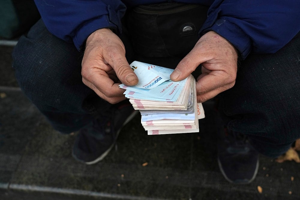 A street money exchanger poses for a photo without showing his face as he counts Iranian banknotes at a commercial district in downtown Tehran, Iran, Friday, Dec. 23, 2022 (AP)