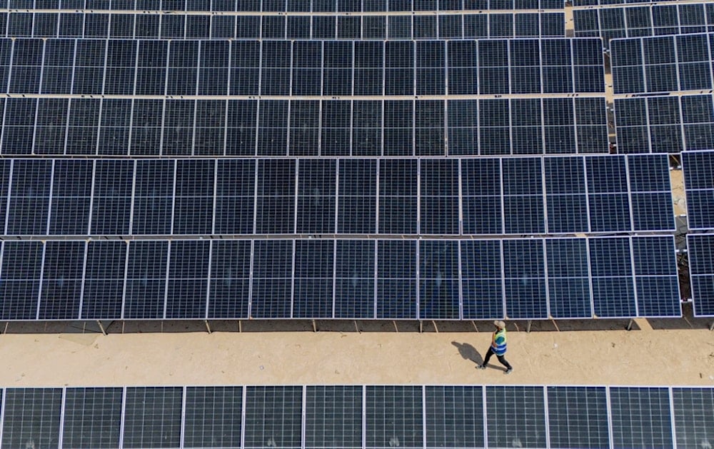 A worker walks past panels at a newly opened industrial-scale solar power plant in Karbala, Iraq, Wednesday, September 17, 2025. (AP Photo/Anmar Khalil)