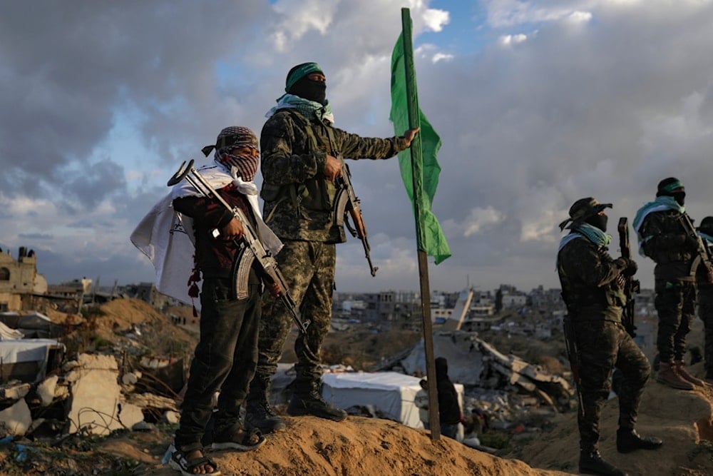 A boy holds an AK-47 rifle as he stands next to a Hamas fighter ahead of the militant group handing over four bodies to the Red Cross in Khan Younis, southern Gaza Strip, Thursday, Feb. 20, 2025.