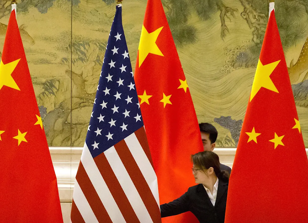 Chinese staffers adjust the US and Chinese flags before the opening session of trade negotiations between US and Chinese trade representatives in Beijing on February 14, 2019. (AP)