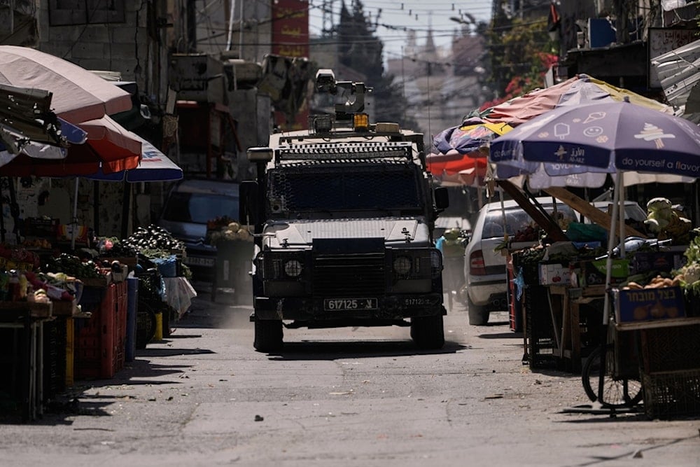 An Israeli armored vehicle moves on a street of a local market during a military raid in the West Bank refugee camp of Balata, Wednesday, October 8, 2025 (AP)
