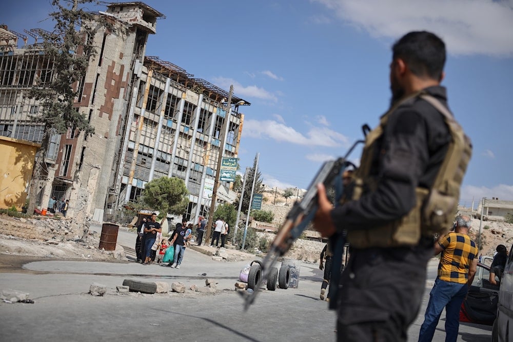 Syrian security forces stand guard as residents leave the Sheikh Maqsoud and Achrafieh neighborhoods of Aleppo, Syria, Tuesday, Oct. 7, 2025 (AP)