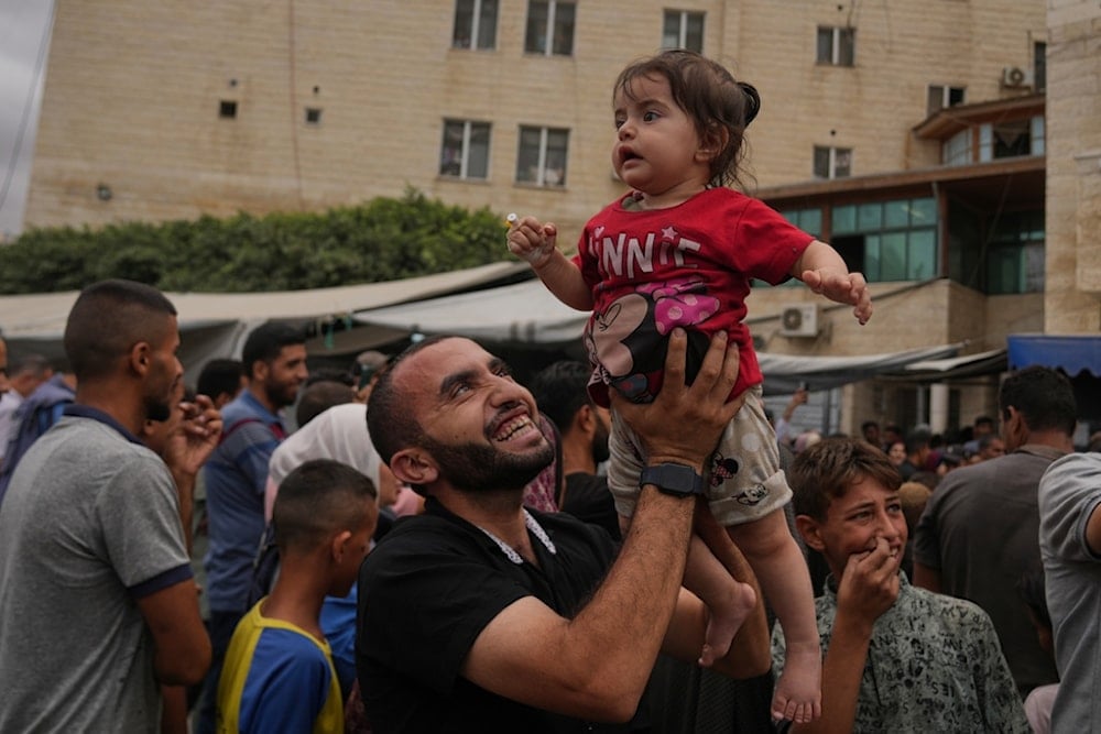 Palestinians celebrate following the announcement of the agreement to the first phase of a peace plan to pause the fighting, outside Al-Aqsa Hospital in Deir al-Balah, central Gaza Strip, Thursday, October 9, 2025 (AP)
