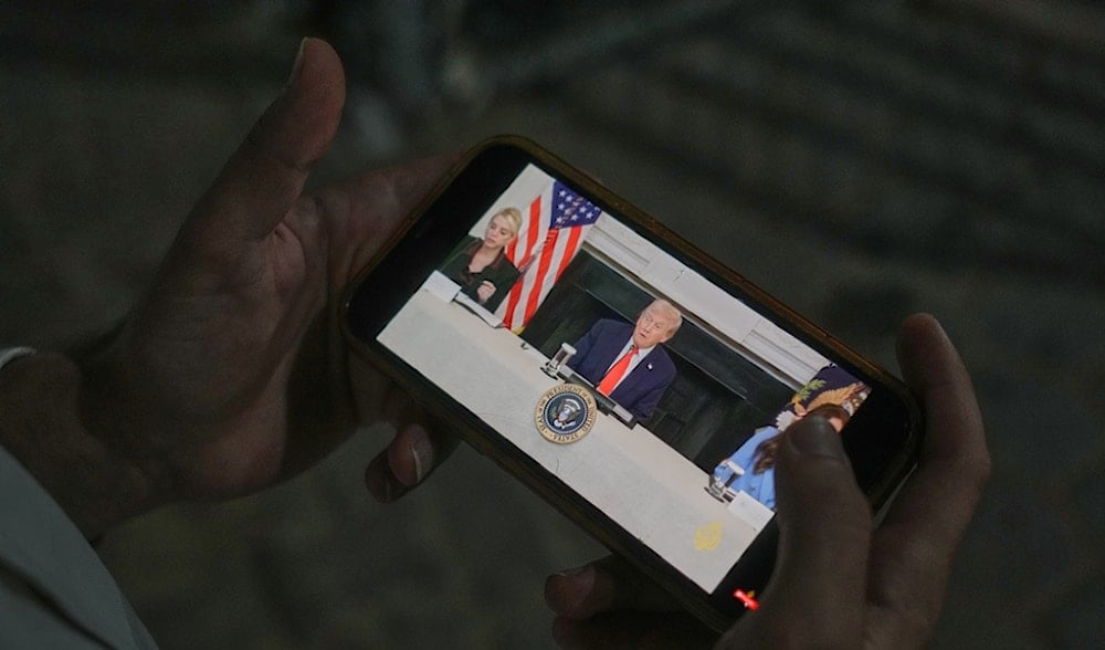 Palestinian paramedic Saeed Awad looks at his phone displaying an image of US President Donald Trump as he stands at Al-Aqsa Hospital, in Deir al-Balah, in the central Gaza Strip, Thursday, Oct. 9, 2025. (AP)