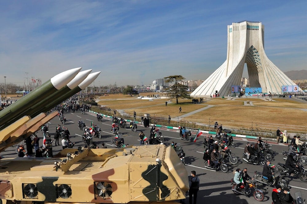 Iranians drive past missiles by their motorcycle during a rally marking the 42nd anniversary of the Islamic Revolution, at Azadi (Freedom) Square in Tehran, Iran, Wednesday, February 10, 2021 (AP)