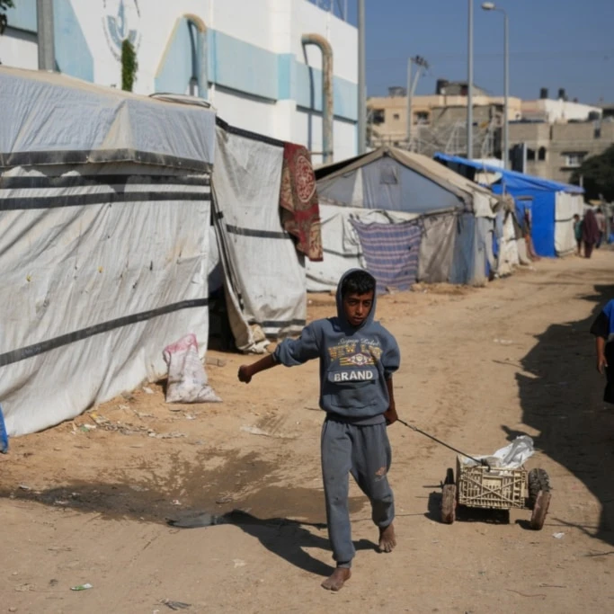 A Palestinian child pulls a cart between tents temporarily erected in a camp in Deir al‑Balah, central Gaza Strip, Saturday, November 1, 2025 (AP)