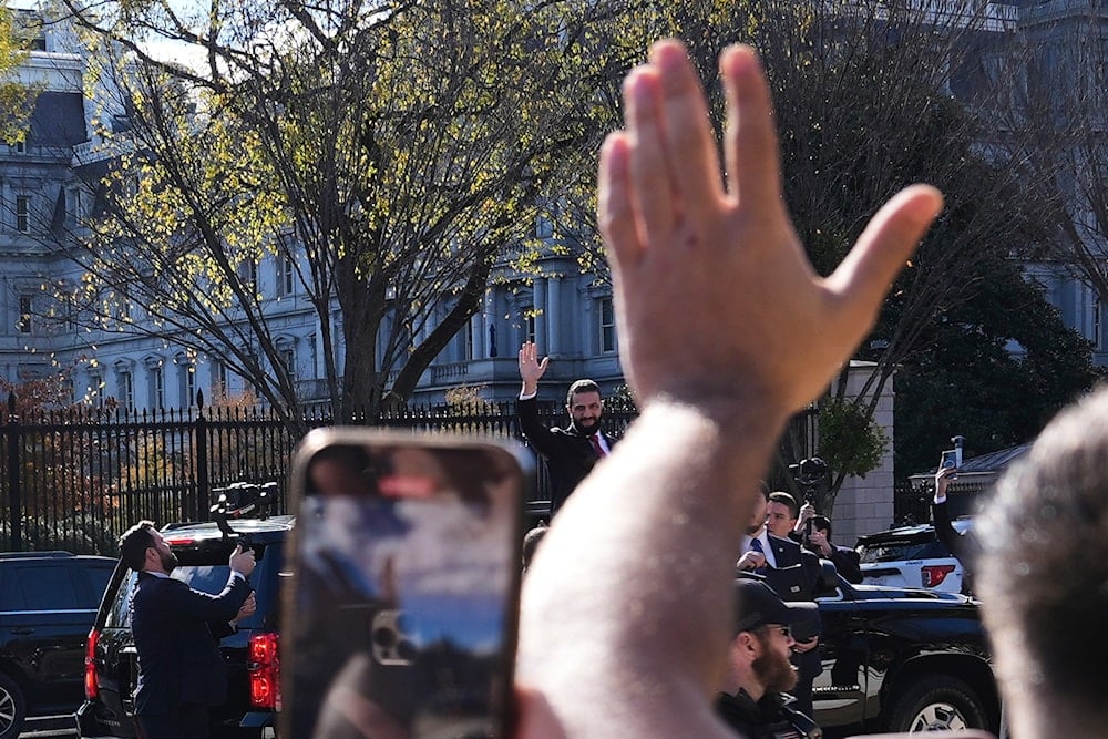 Syria's President Ahmed al-Sharaa, center, waves to supporters from a vehicle outside of the White House, Monday, Nov. 10, 2025, in Washington (AP)