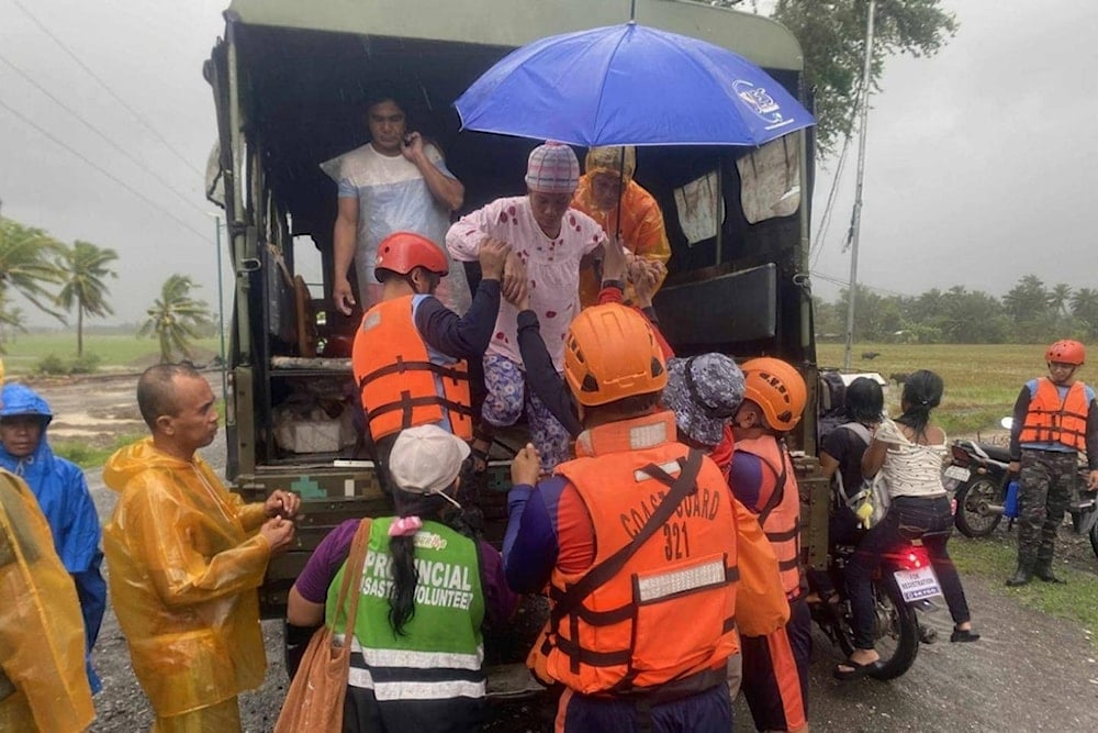 In this photo provided by the Philippine Coast Guard, rescuers evacuate residents in Sablayan, Occidental Mindoro province of the Philippines as Typhoon Fung-wong batters the country on Sunday, November 9 2025. (Philippine Coast Guard via AP)