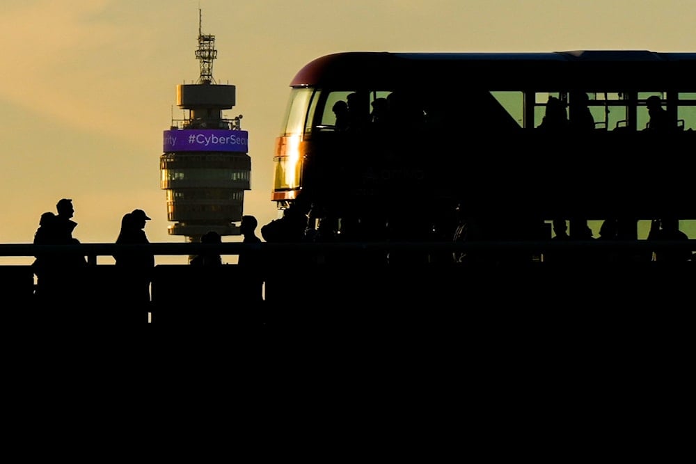 People walk and a red double-decker bus drives on the London Bridge during evening rush hour as BT Tower is seen in the background, on October 6, 2025, in London. (AP Photo/Julia Demaree Nikhinson)