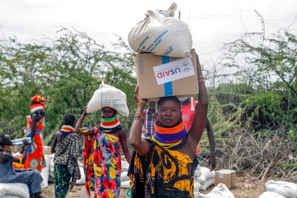 Local residents carry boxes and sacks of food distributed by the United States Agency for International Development (USAID), in Kachoda, Turkana area, northern Kenya, Saturday, July 23, 2022. (AP Photo/Desmond Tiro)