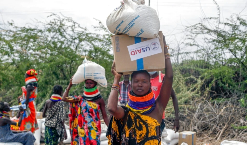 Local residents carry boxes and sacks of food distributed by the United States Agency for International Development (USAID), in Kachoda, Turkana area, northern Kenya, Saturday, July 23, 2022. (AP Photo/Desmond Tiro)