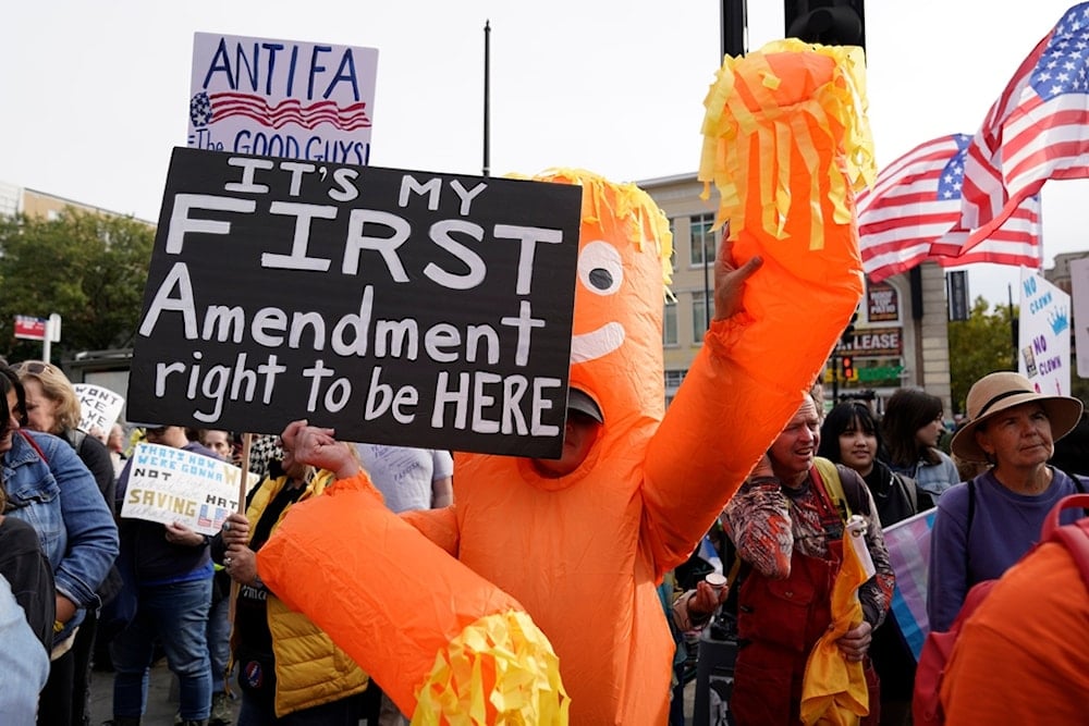 Demonstrators carry signs as they rally at the 14th and U street corridor before marching to the national Mall during a No Kings protest in Washington, Saturday, October 18, 2025 (AP)