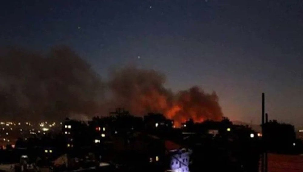 **Caption:** Smoke and flames rise over Damascus's Mezzeh district after a series of nighttime explosions shook the area. (Agencies)