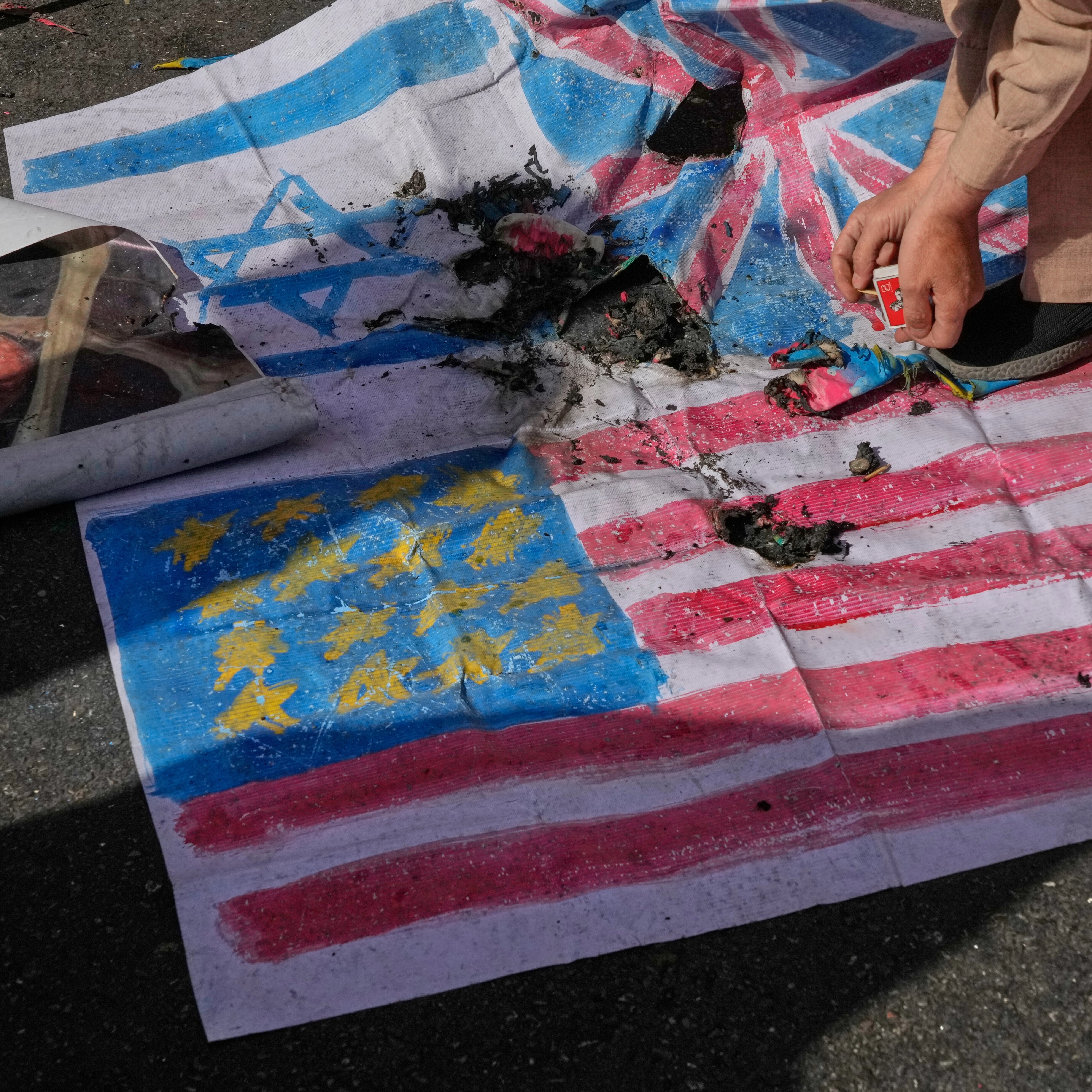 A demonstrator burns the US and Israeli flags and a satirized portrait of the Israeli Prime Minister Benjamin Netanyahu during an annual rally in front of the former US Embassy in Tehran,  Nov. 4, 2025 (AP)