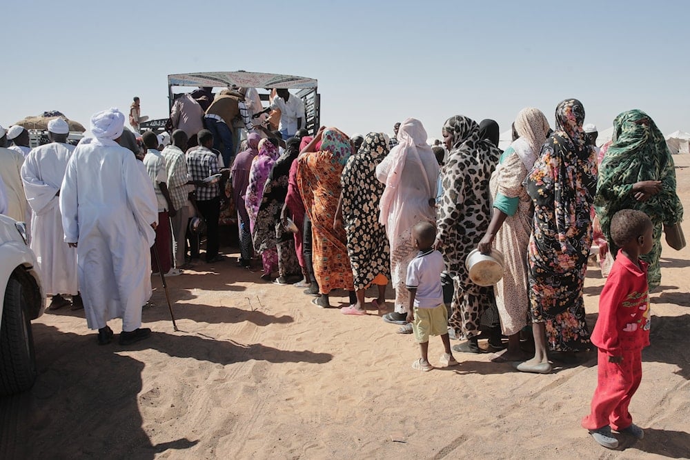 Sudanese families displaced from El-Fasher line up to receive food aid at the newly established El-Afadh camp in Al Dabbah, in Sudan's Northern State, Sunday, Nov. 16, 2025 (AP)