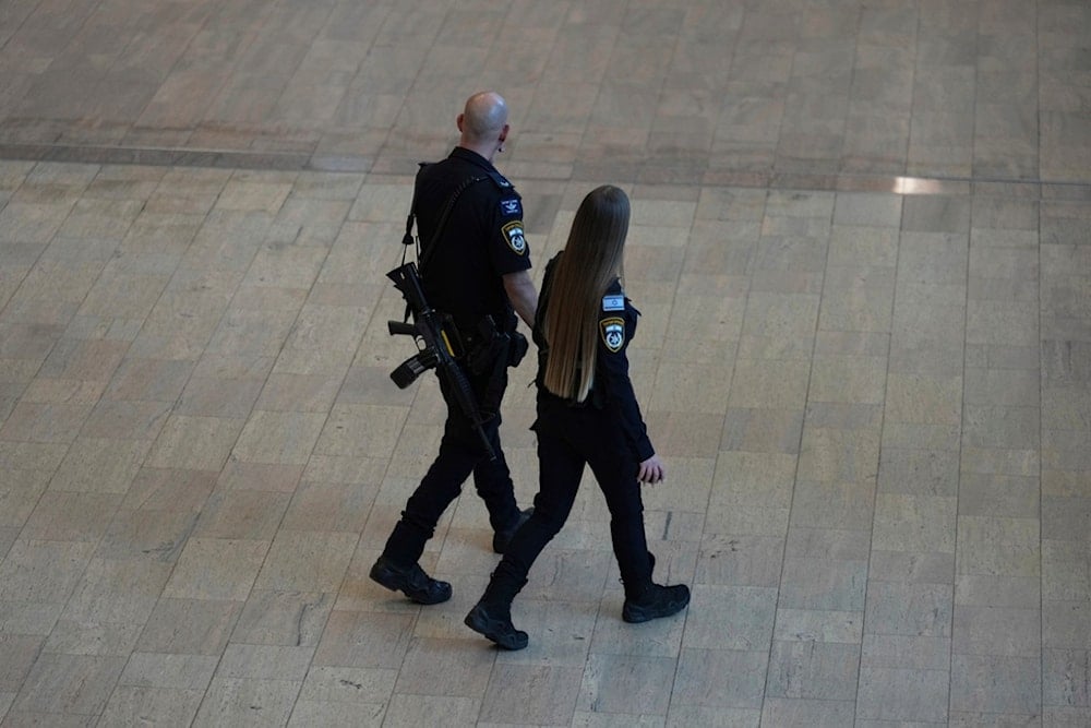 Israeli police walk through Ben Gurion Airport, empty of passengers after all flights were canceled following an Israeli military strike on Iran, near Tel Aviv, Israel, Friday, June 13, 2025. (AP Photo/Ariel Schalit)