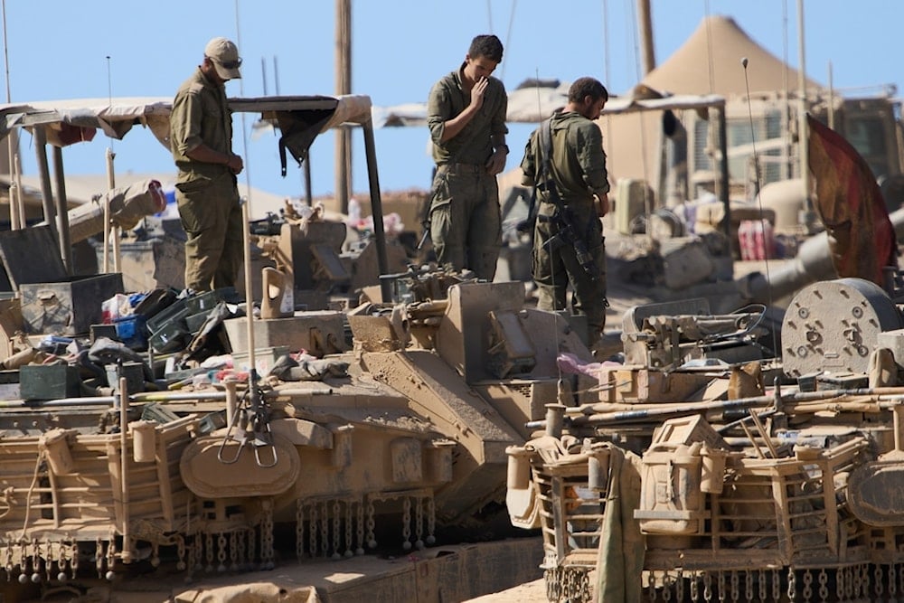 Israeli soldiers work on their tanks at a gathering point near the Gaza Strip, in southern occupied Palestine, Saturday, October 11, 2025 (AP)