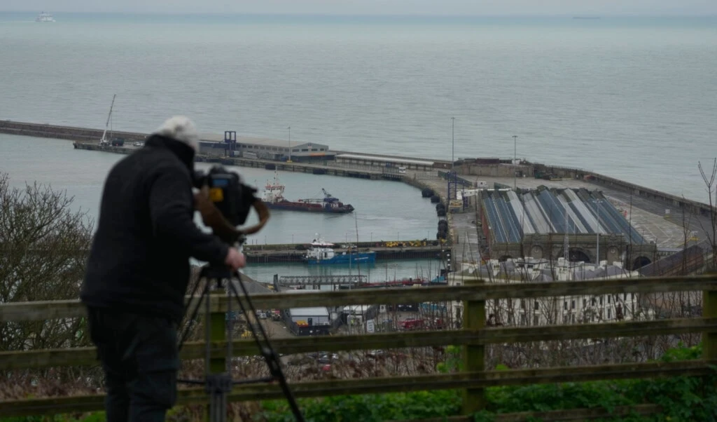 A cameraman films the migrant processing centre in Dover, Kent, England, Tuesday, March 7, 2023. (AP)