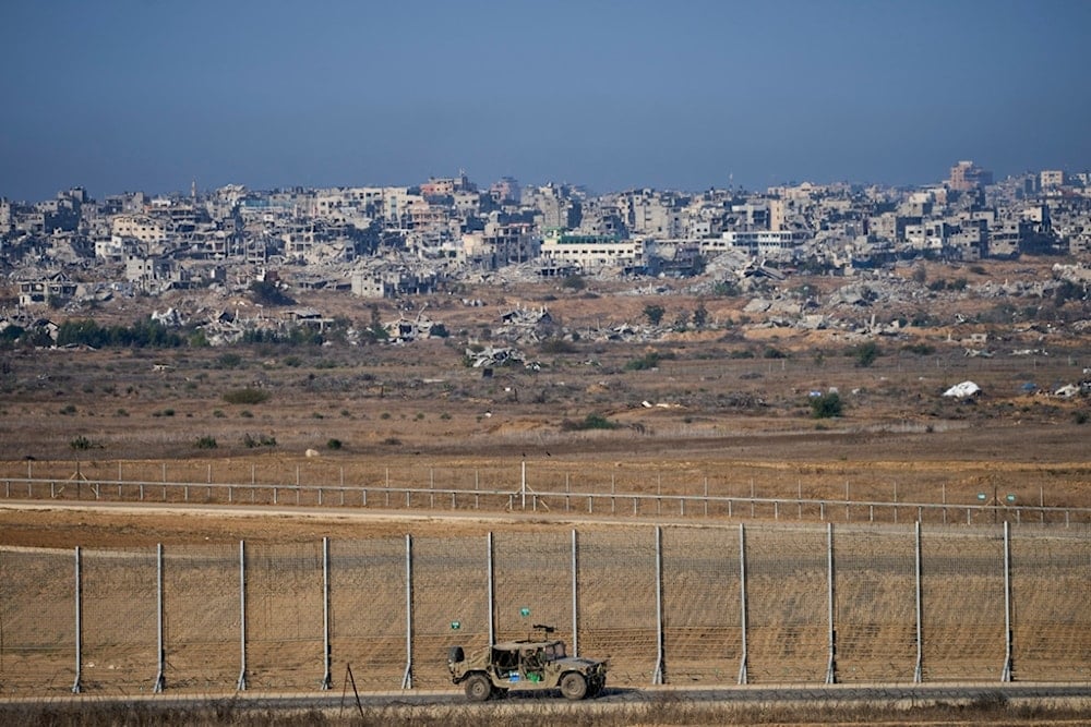 An Israeli army vehicle moves along the Gaza Strip, as seen from southern occupied Palestine on Tuesday, November 18, 2025 (AP)