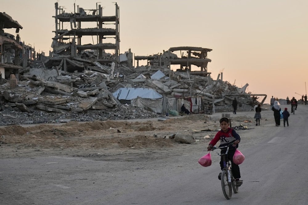 A boy rides his bicycle along a damaged street in the Al-Shati camp in Gaza City, Tuesday, November 18, 2025 (AP)