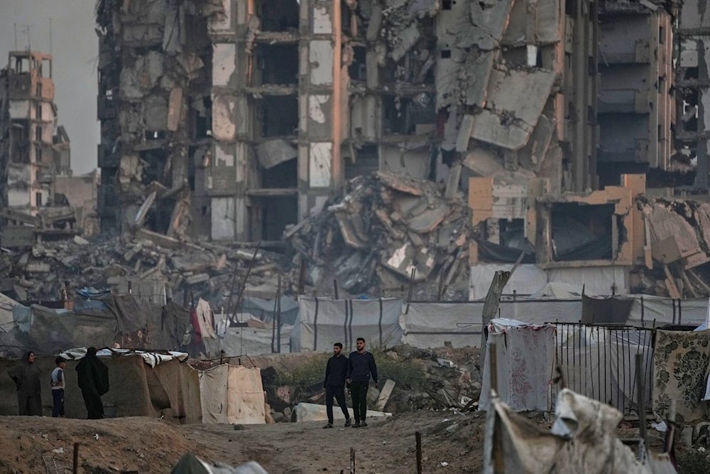 Two men walk past destroyed apartment buildings at the Al-Shati camp in Gaza City, Tuesday, Nov. 18, 2025 (AP)
