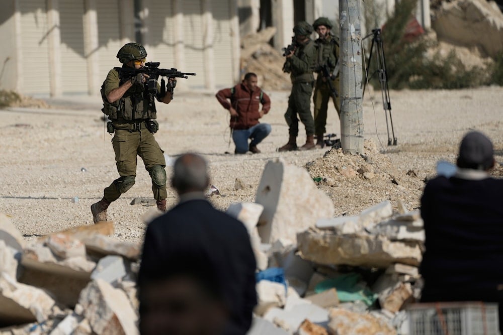 An Israeli soldier aims his weapon to disperse people taking part in a protest calling for the return of displaced Palestinians to their houses in the Nur Shams refugee camp in the West Bank city of Tulkarm on Tuesday, Nov. 18, 2025 (AP)
