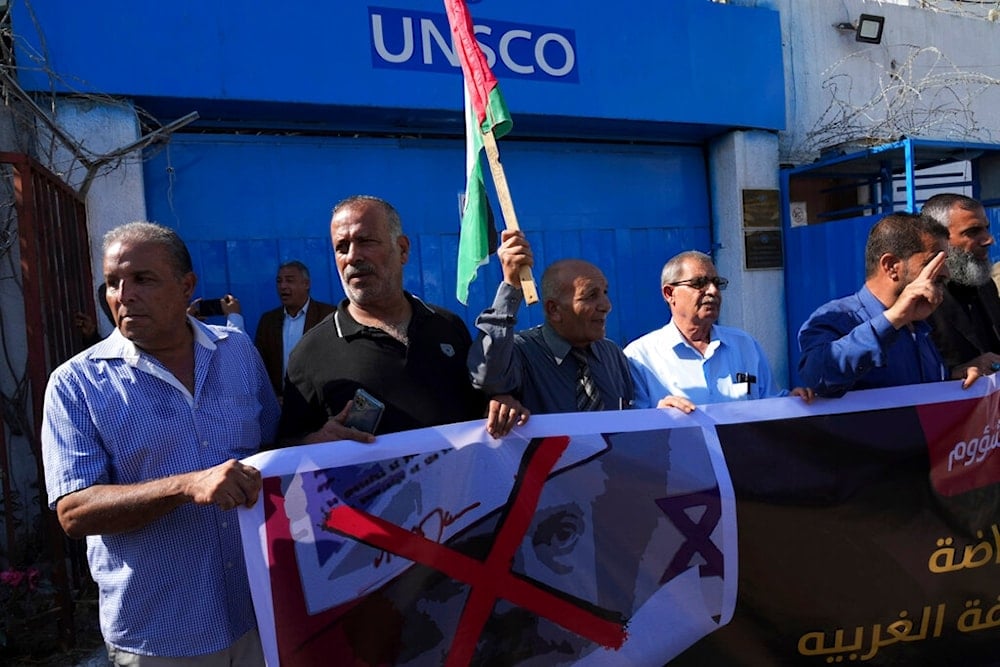 Demonstrators wave their national flag while hold a defaced picture of British Foreign Secretary Lord Arthur Balfour during a protest against the 105th anniversary of Britain's Balfour Declaration in Gaza City, Wednesday, November 2, 2022 (AP)
