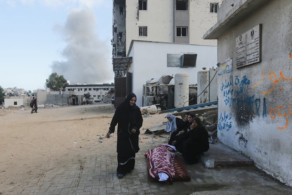 Mourners sit beside a body of a Palestinian killed in an Israeli army strike, at Shifa Hospital in Gaza City Wednesday, Oct. 29, 2025 (AP)