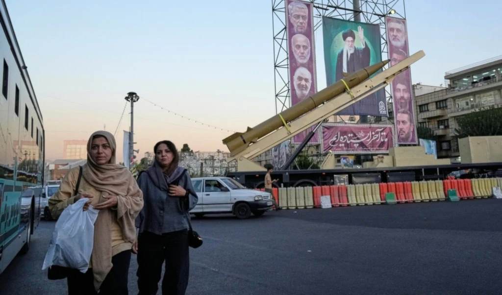 People walk past a domestically-built missile "Khaibar-buster," and banners showing portraits of Iranian Leader Ayatollah Ali Khamenei, center, and the late armed forces commanders at Baharestan Square in Tehran, Thursday, September 25, 2025