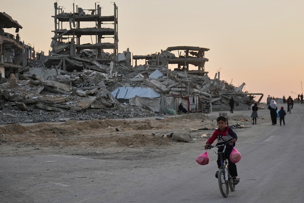 A boy rides his bicycle along a damaged street in the Al-Shati camp in Gaza City, Tuesday, Nov. 18, 2025 (AP)