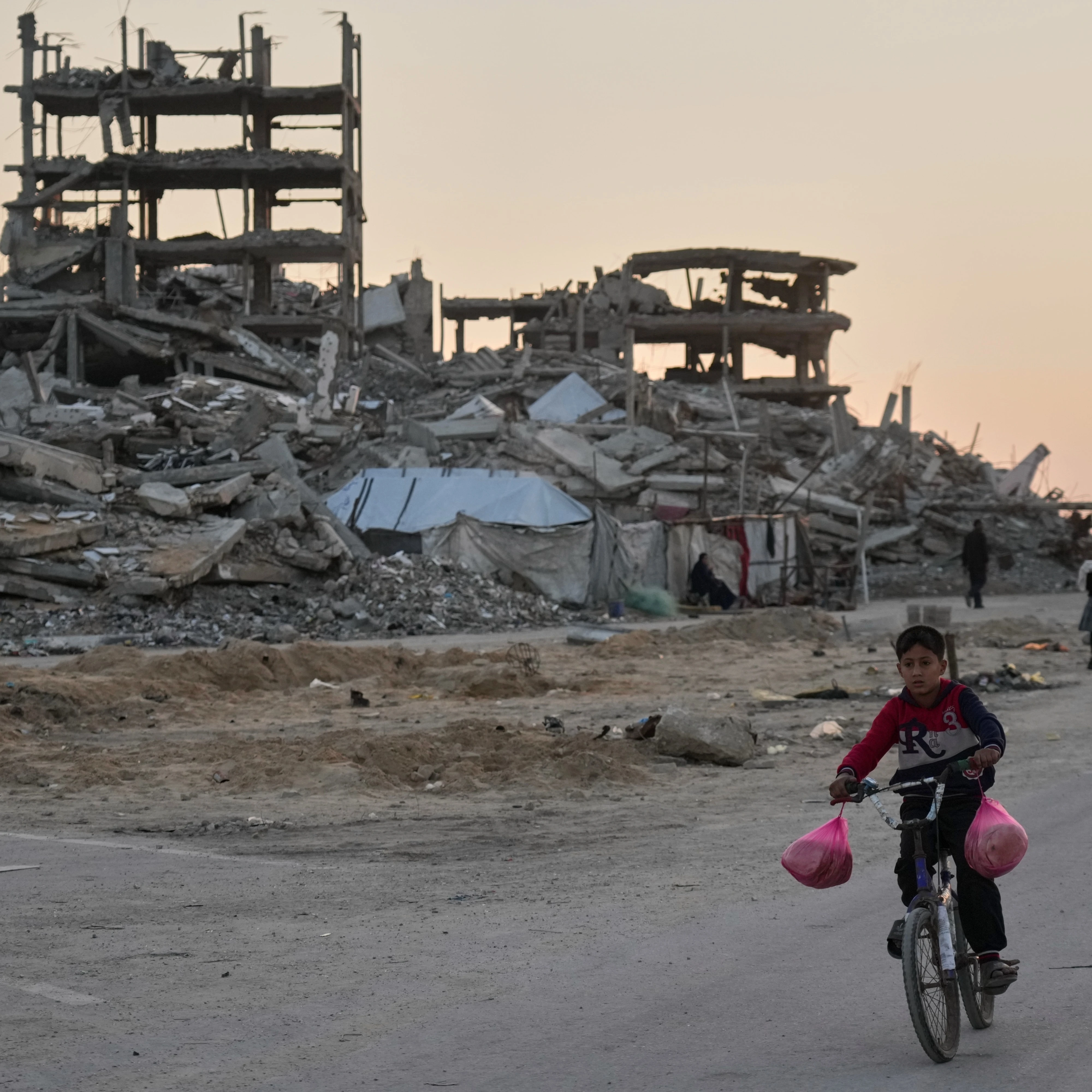 A boy rides his bicycle along a damaged street in the Al-Shati camp in Gaza City, Tuesday, Nov. 18, 2025 (AP)