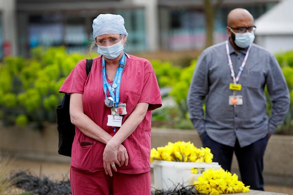 Members of NHS staff gather for a minute of silence and reflection at St Thomas' hospital in London, Tuesday, March 23, 2021. (AP)