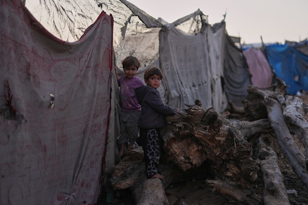 Palestinian children look at the camera as they play in a makeshift camp for displaced people in Zawayda, in the central Gaza Strip, Tuesday, November 18, 2025. (AP Photo/Abdel Kareem Hana)