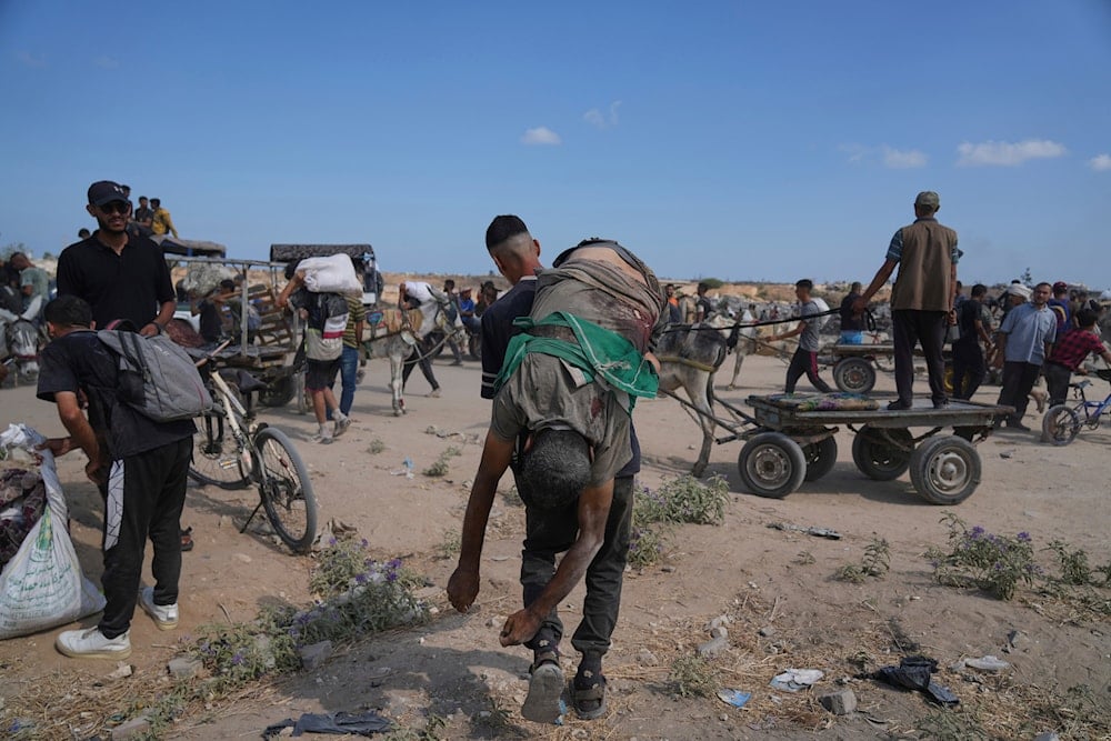 A Palestinian carries the body of a man killed while trying to receive aid near a distribution center operated by the US-backed Gaza Humanitarian Foundation (GHF) in the Netzarim Axis, in the Gaza Strip, Occupied Palestine, Aug. 4, 2025 (AP)