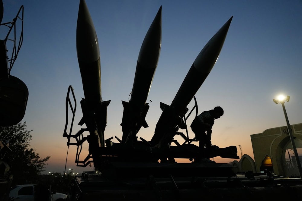A boy tries to stand near missiles displayed in the National Aerospace Park of the Revolutionary Guard, just outside Tehran, Iran, Thursday, Nov. 13, 2025 (AP)