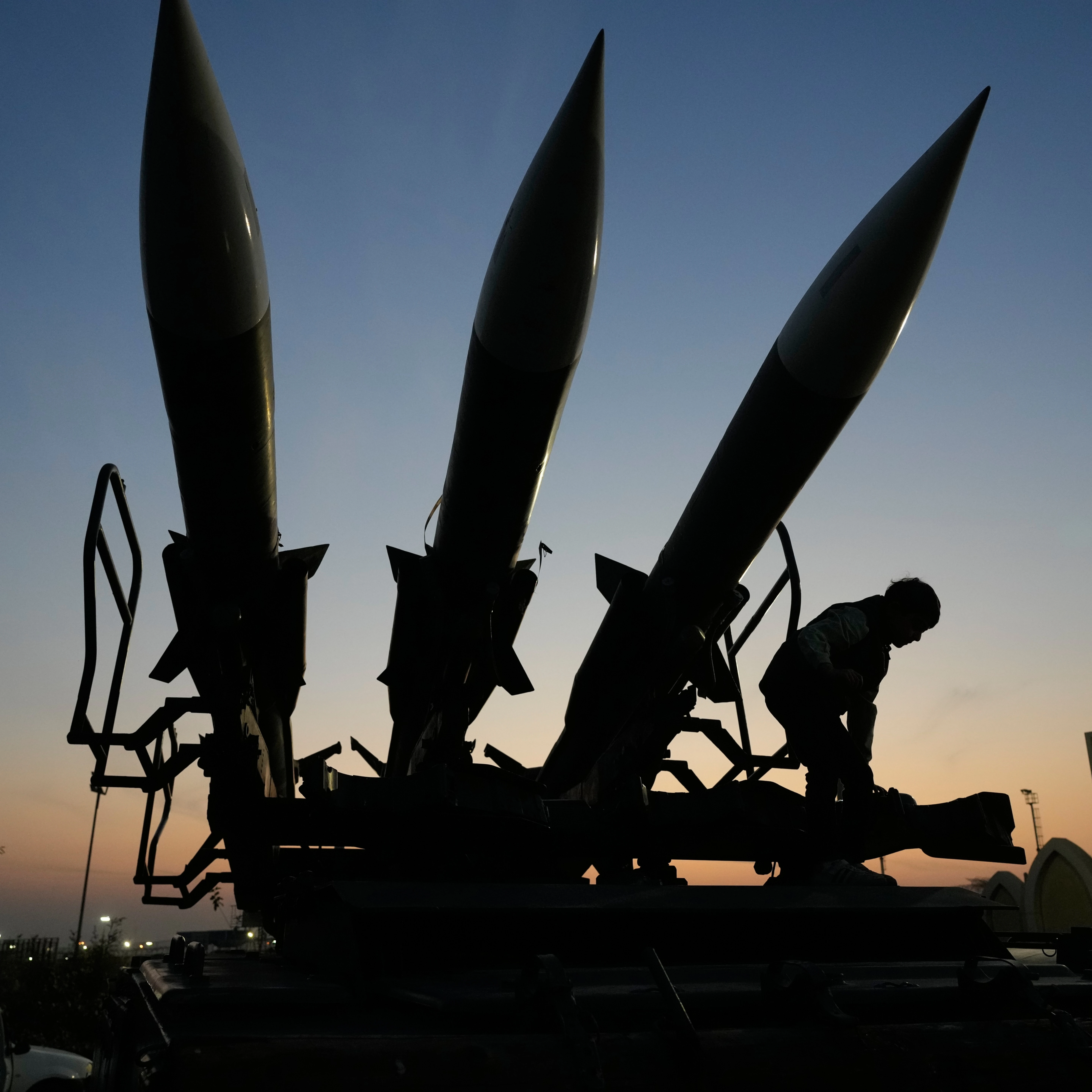 A boy tries to stand near missiles displayed in the National Aerospace Park of the Revolutionary Guard, just outside Tehran, Iran, Thursday, Nov. 13, 2025 (AP)