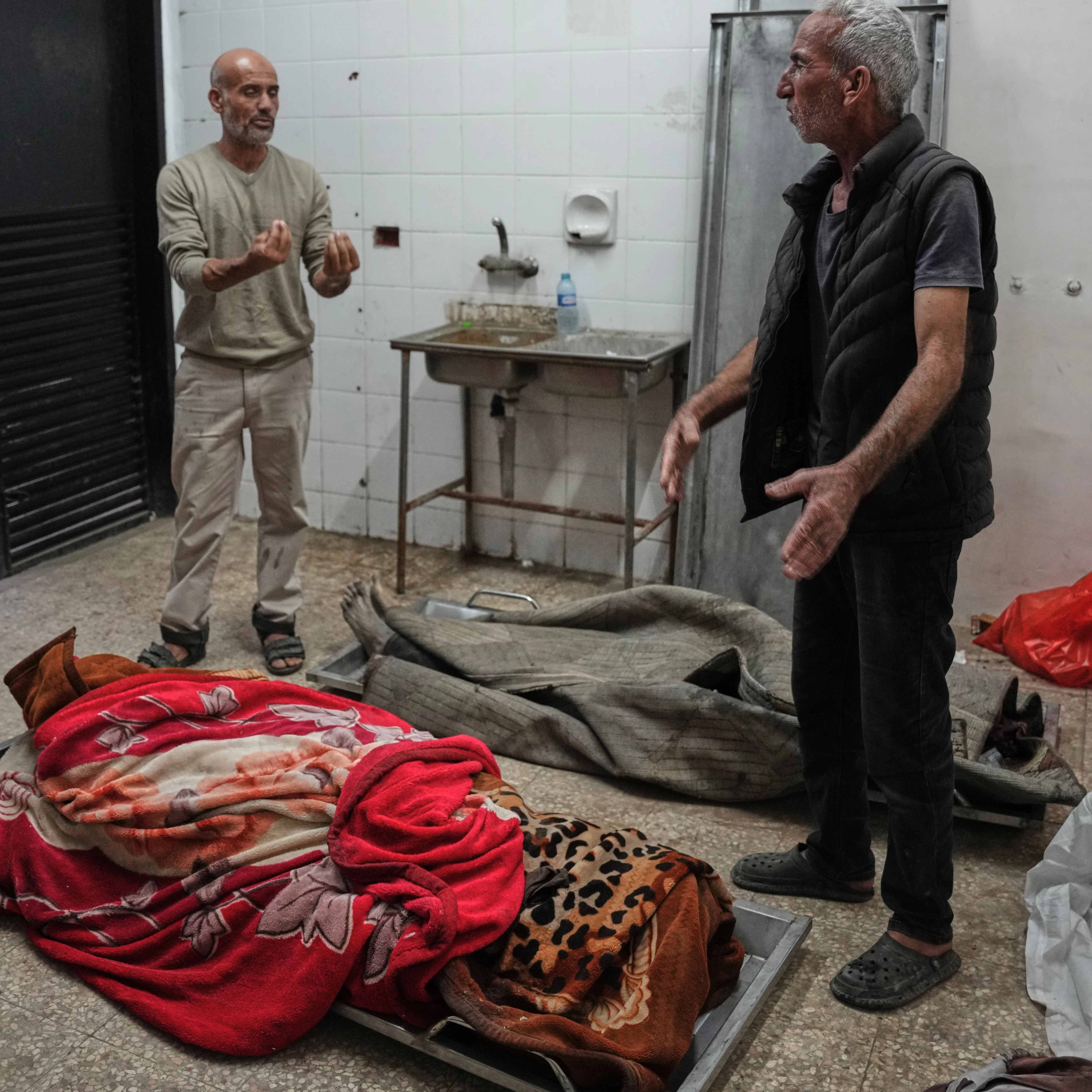 Palestinians check the bodies of people killed in Israeli strikes on the Gaza Strip at the morgue of Al-Aqsa Hospital in Deir al-Balah, Saturday, Nov. 22, 2025 (AP)