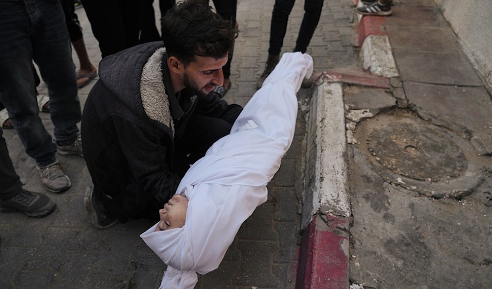 A man carries the body of a child from the Azzam family, killed in Israeli strikes, during her funeral at Shifa Hospital in Gaza City, Nov. 20, 2025. (AP)