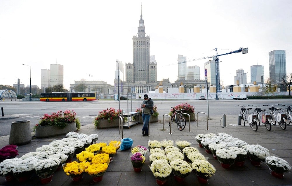 A man stands by bouquets of flowers, after Poland's government closed all cemeteries in an attempt to curb the spread of COVID-19, in Warsaw, Poland, Sunday, November 1, 2020 (AP Photo/Czarek Sokolowski)