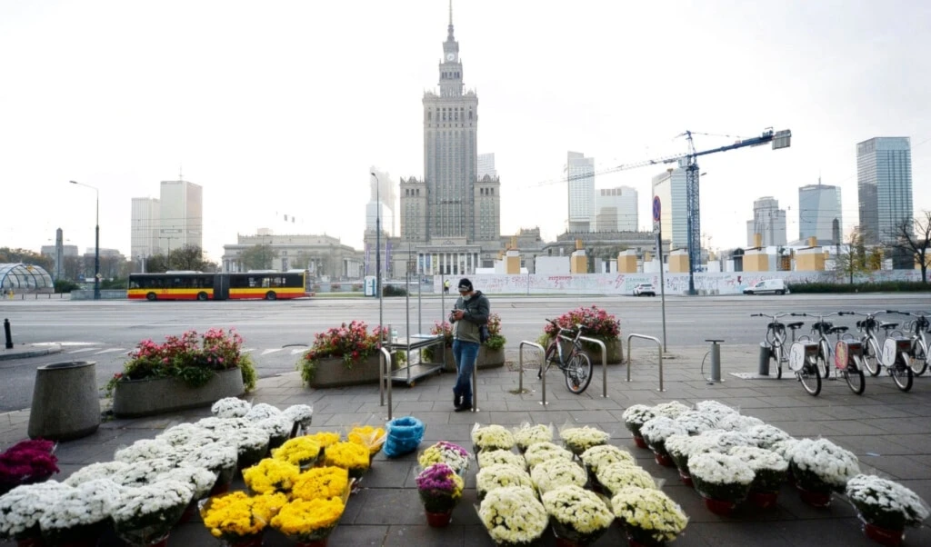 A man stands by bouquets of flowers, after Poland's government closed all cemeteries in an attempt to curb the spread of COVID-19, in Warsaw, Poland, Sunday, November 1, 2020 (AP Photo/Czarek Sokolowski)
