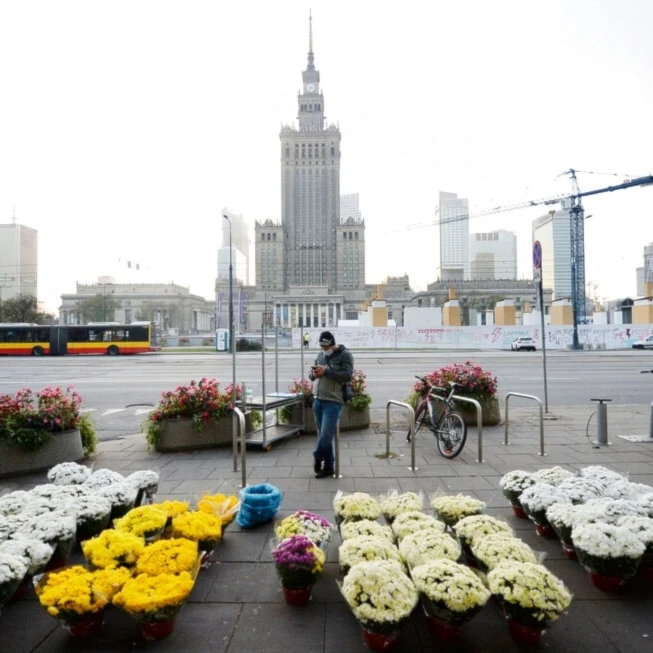 A man stands by bouquets of flowers, after Poland's government closed all cemeteries in an attempt to curb the spread of COVID-19, in Warsaw, Poland, Sunday, November 1, 2020 (AP Photo/Czarek Sokolowski)